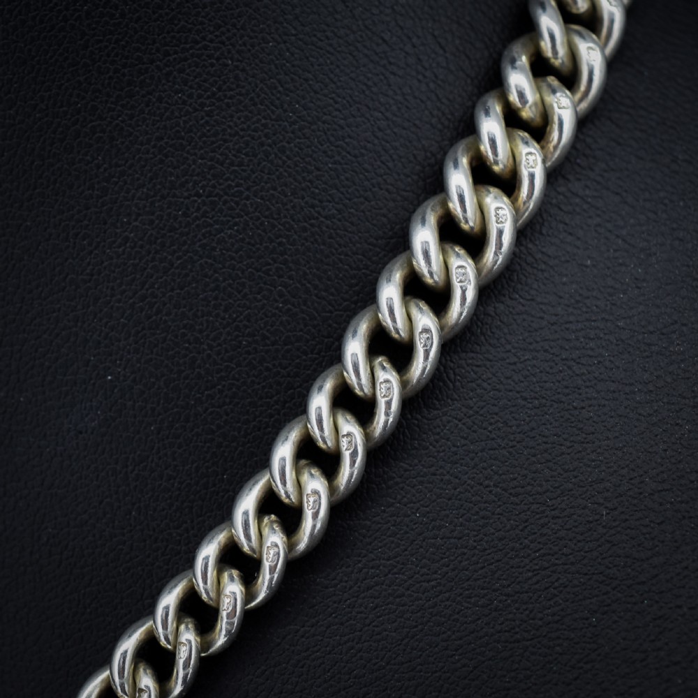 An antique sterling silver heavy curb link Albert watch chain featuring a T-bar and swivel clasp, displayed flat. View IV