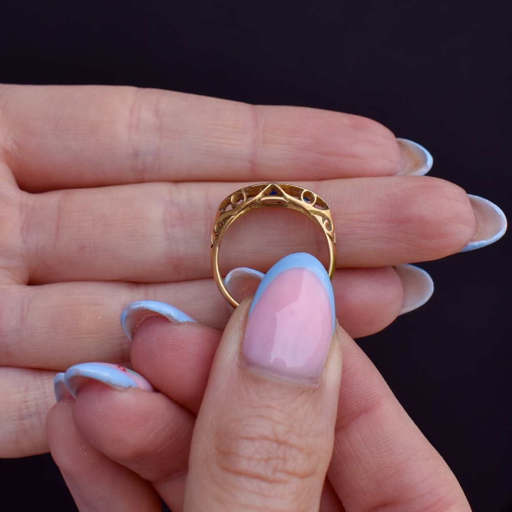 An Edwardian 18ct yellow gold boat ring set with three blue sapphires and two diamonds in an elongated marquise-shaped mount. View IV