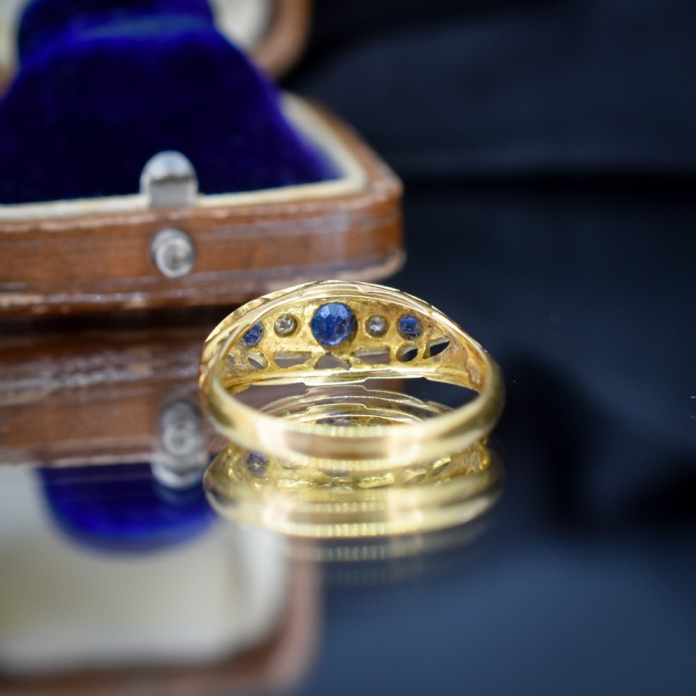 An Edwardian 18ct yellow gold boat ring set with three blue sapphires and two diamonds in an elongated marquise-shaped mount. View XI