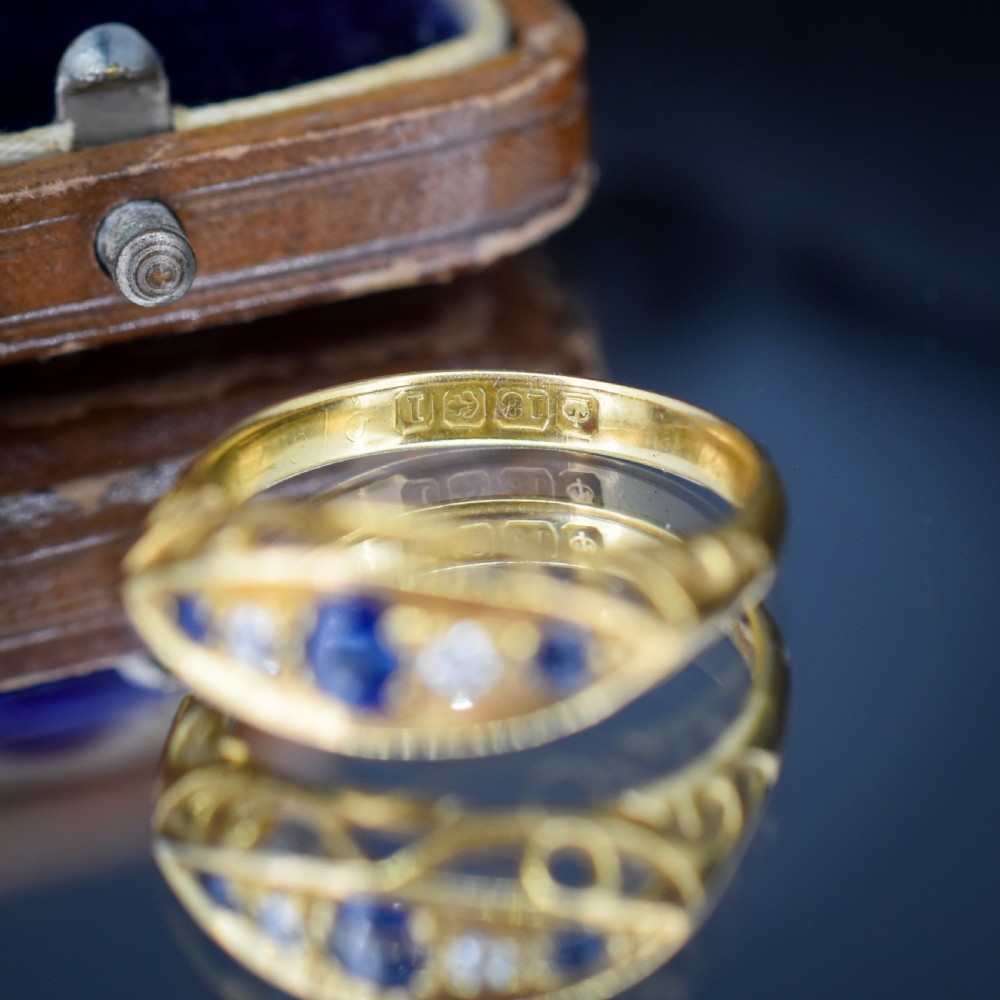 An Edwardian 18ct yellow gold boat ring set with three blue sapphires and two diamonds in an elongated marquise-shaped mount. View XII