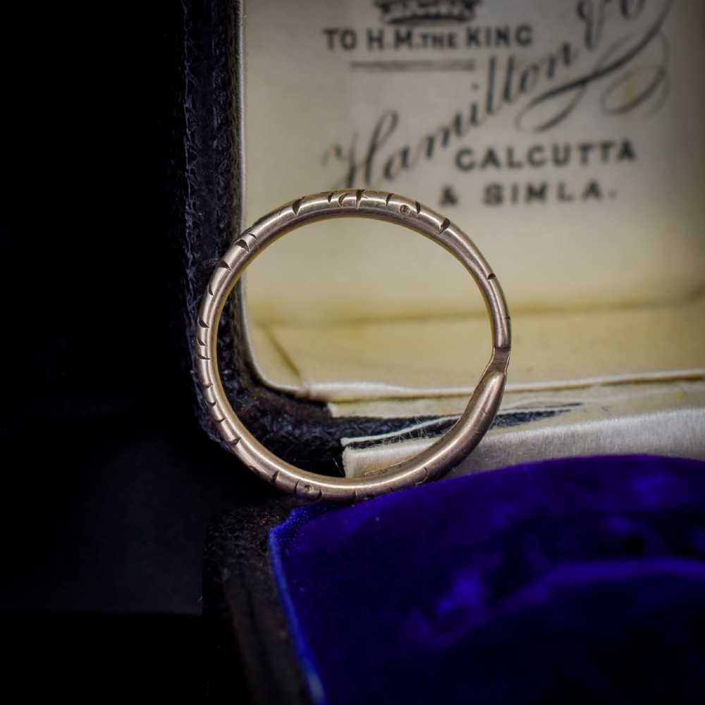 An antique 9ct yellow gold split ring measuring 17mm with hand-engraved notch details around the outer circumference.