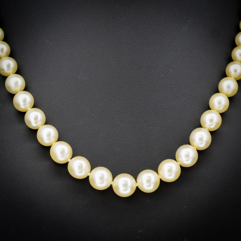 A graduated strand of cream pearls featuring a yellow gold fluted clasp. View III