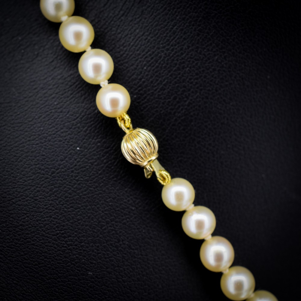A graduated strand of cream pearls featuring a yellow gold fluted clasp. View V
