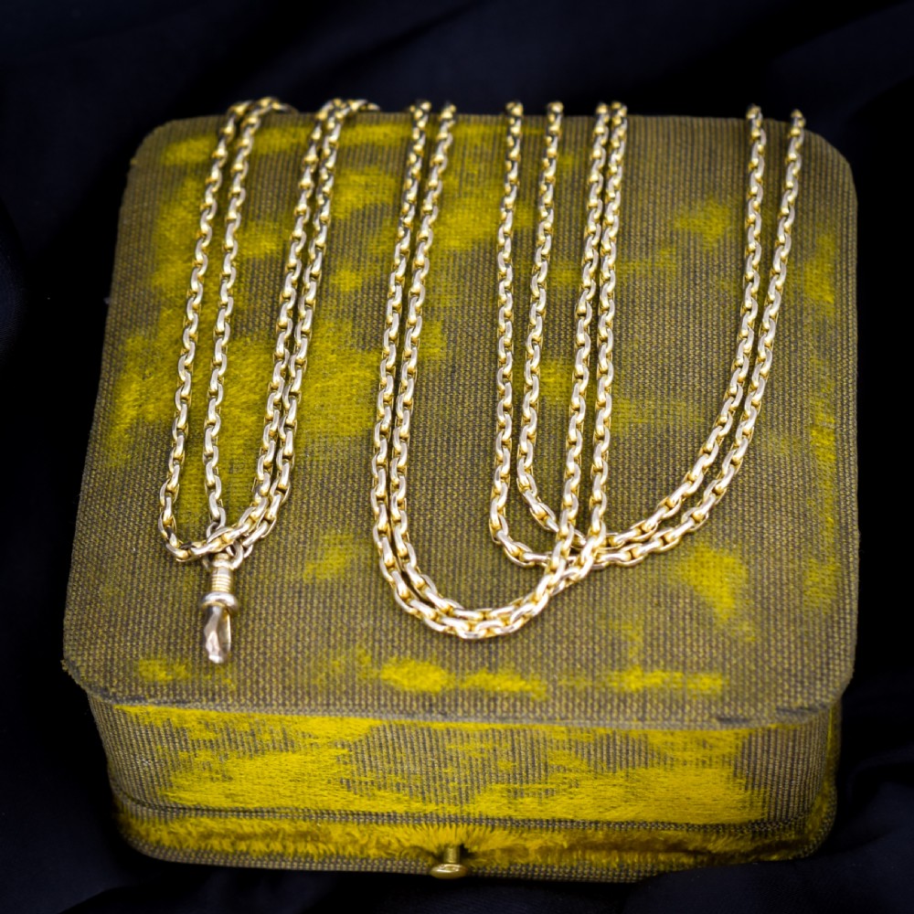 A long 9ct yellow gold faceted link guard chain wrapped in loops beside a swivel dog clip clasp.