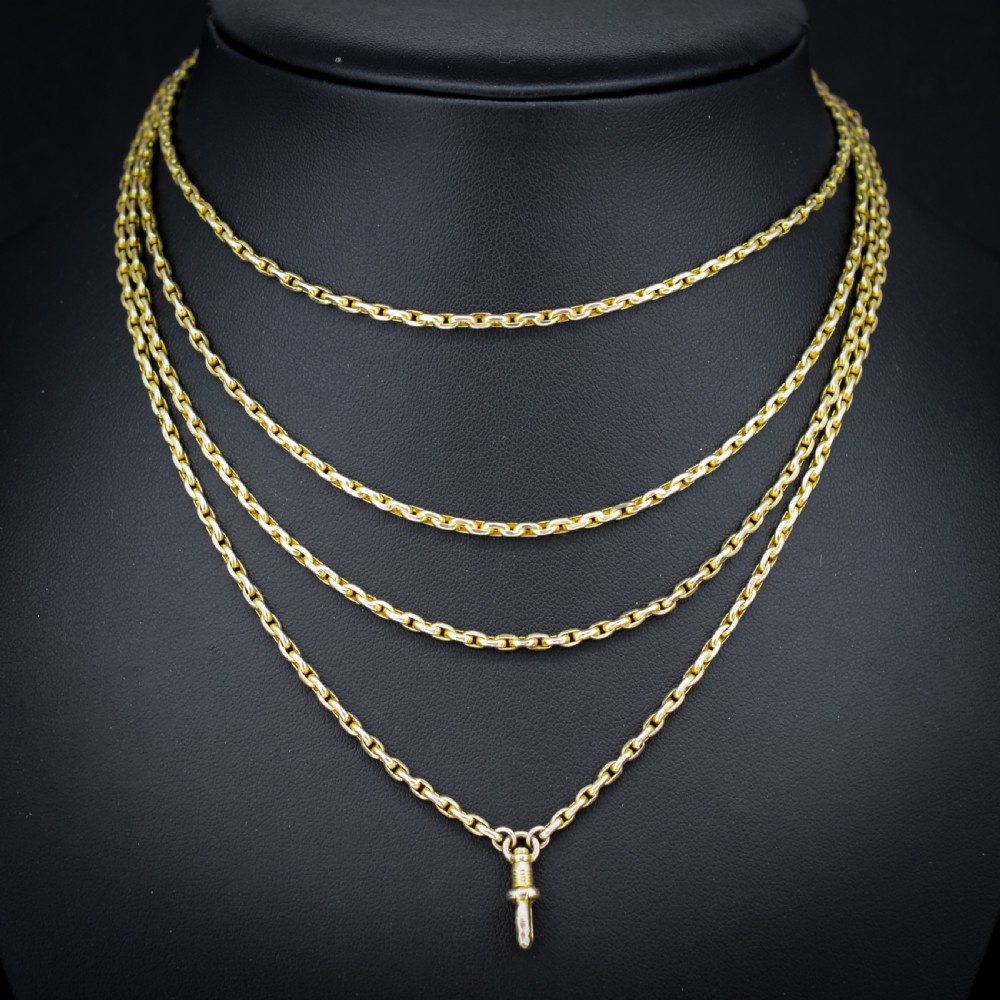 A long 9ct yellow gold faceted link guard chain wrapped in loops beside a swivel dog clip clasp. View II