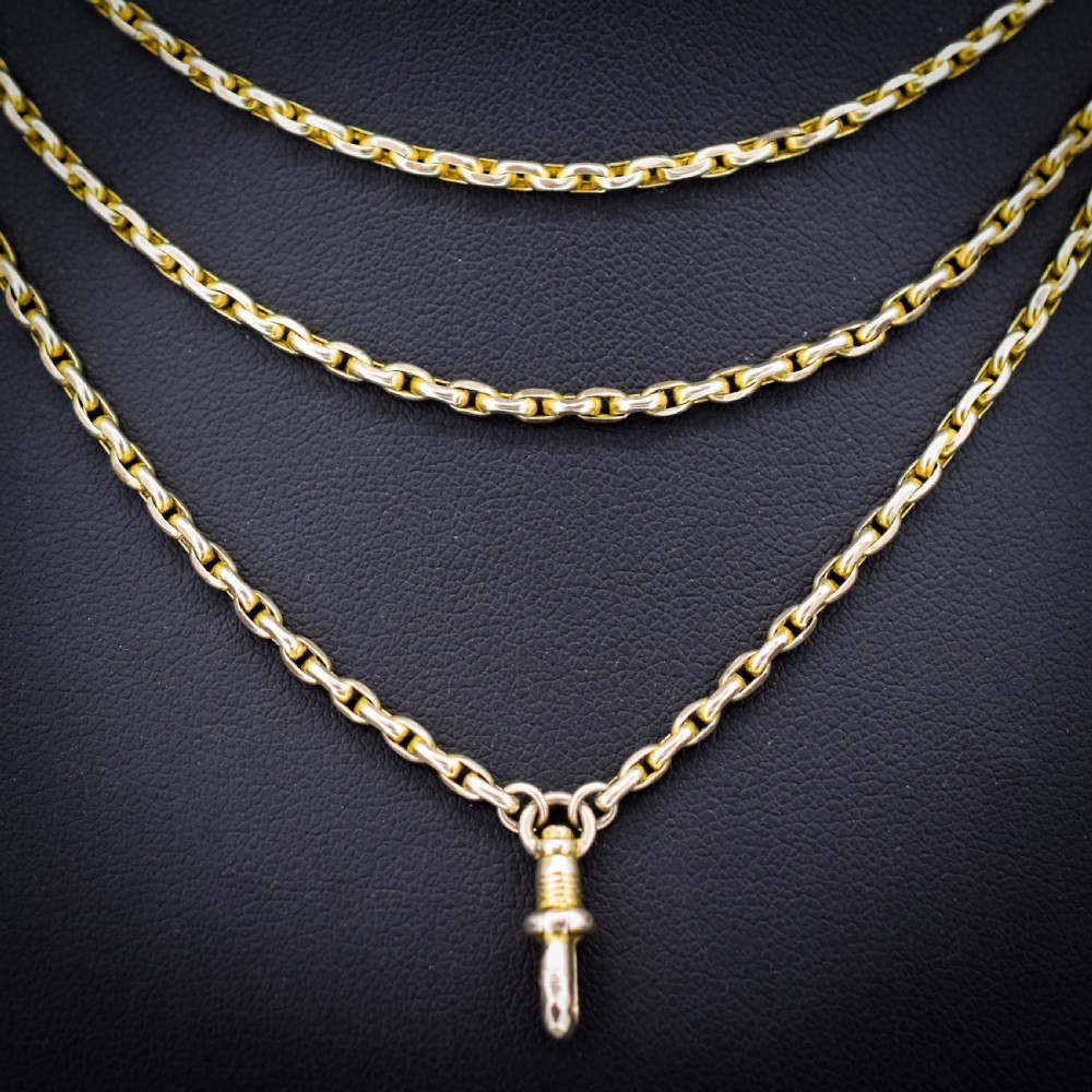 A long 9ct yellow gold faceted link guard chain wrapped in loops beside a swivel dog clip clasp. View III
