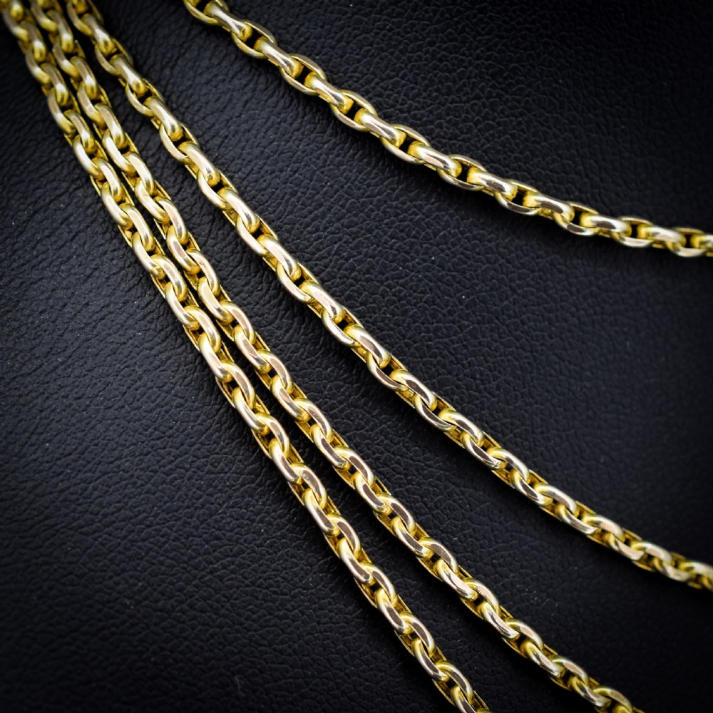 A long 9ct yellow gold faceted link guard chain wrapped in loops beside a swivel dog clip clasp. View IV
