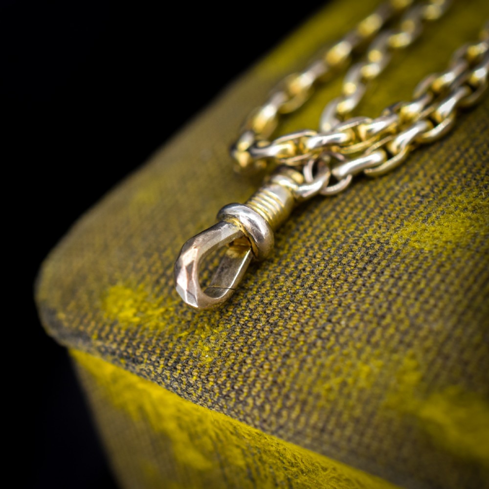 A long 9ct yellow gold faceted link guard chain wrapped in loops beside a swivel dog clip clasp. View V