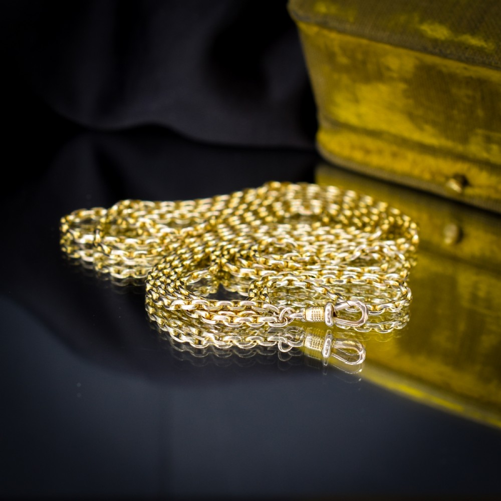 A long 9ct yellow gold faceted link guard chain wrapped in loops beside a swivel dog clip clasp. View VI