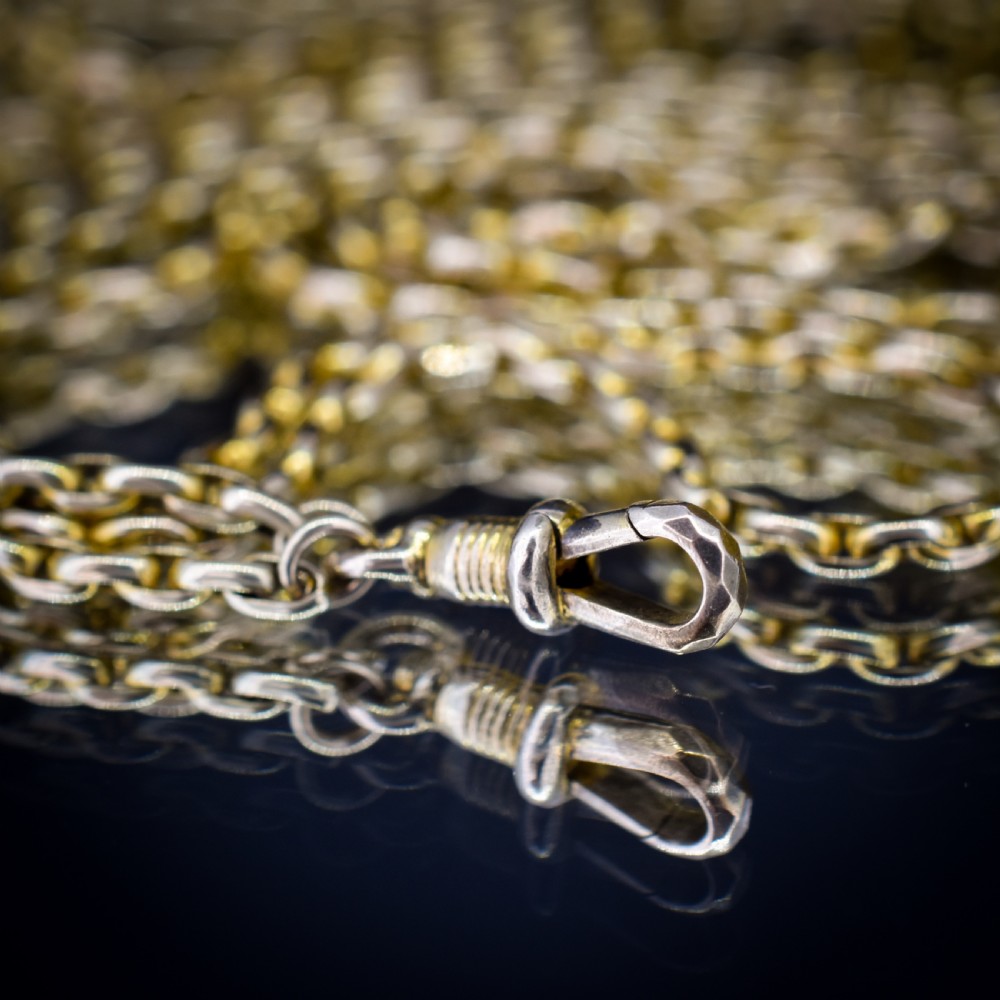 A long 9ct yellow gold faceted link guard chain wrapped in loops beside a swivel dog clip clasp. View VII