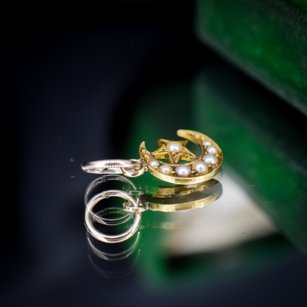 An 18ct gold crescent moon pendant set with seed pearls enclosing a star motif. View V