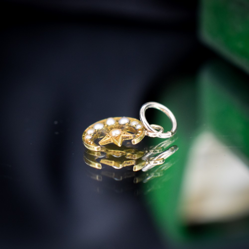An 18ct gold crescent moon pendant set with seed pearls enclosing a star motif. View VI