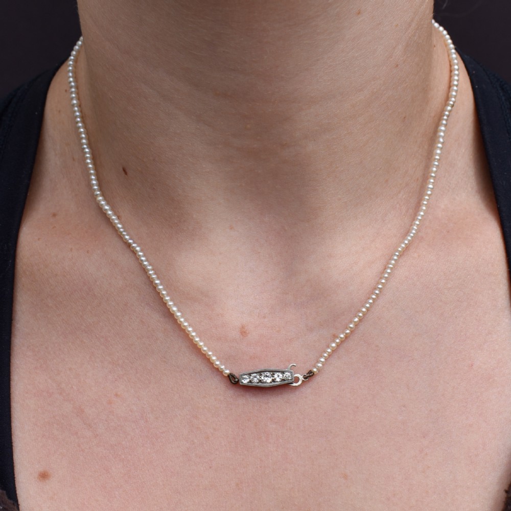 A single strand of graduated cream pearls fitted with an 18ct white gold clasp set with diamonds. View XI