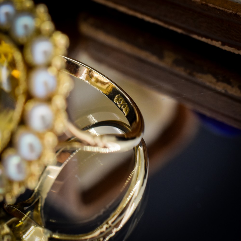 An antique yellow gold ring featuring a central oval faceted yellow citrine stone surrounded by a halo of white seed pearls. View XI