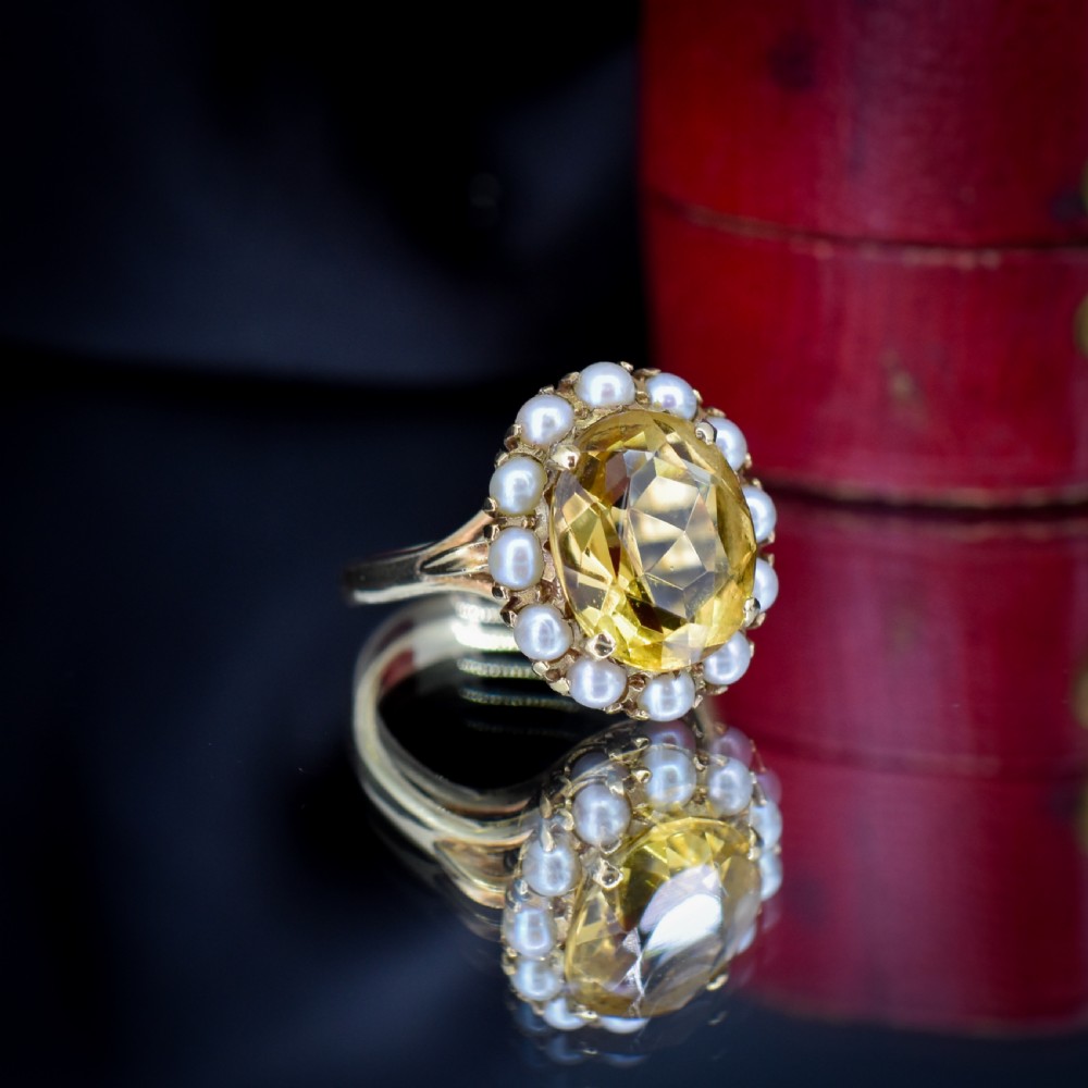 A vintage 9ct gold ring featuring a central oval faceted yellow citrine gemstone surrounded by a halo of small white pearls. View IV