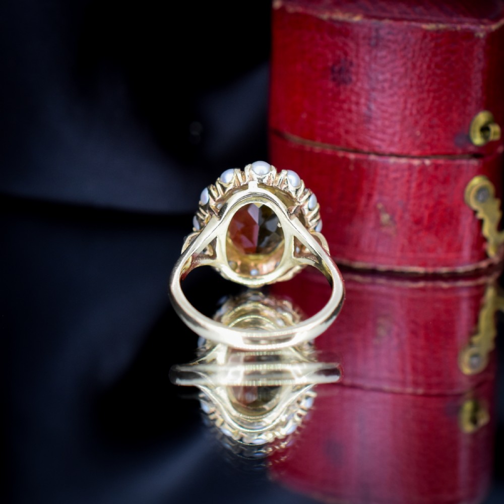 A vintage 9ct gold ring featuring a central oval faceted yellow citrine gemstone surrounded by a halo of small white pearls. View V