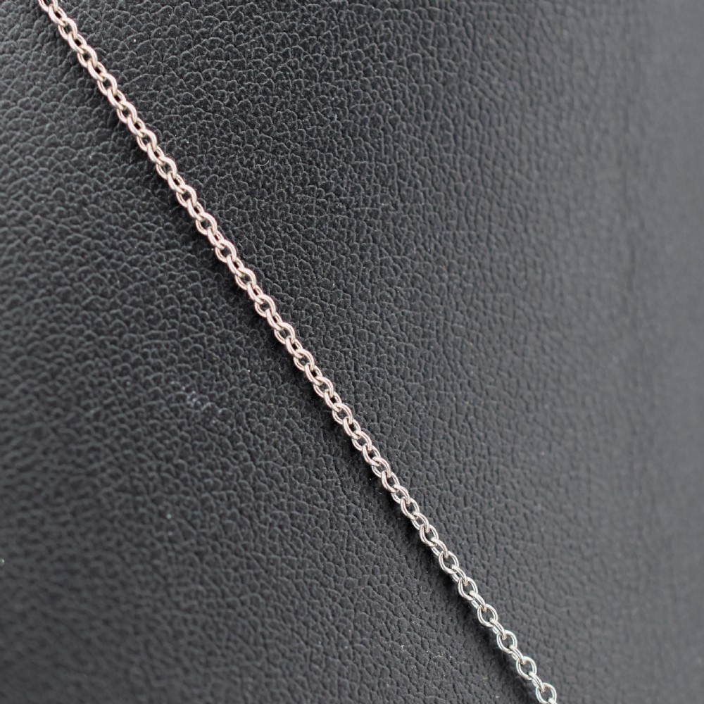 An antique silver pendant necklace featuring an emerald-cut green paste stone surrounded by a clear paste stone halo, suspended from an articulated linear drop. View IV