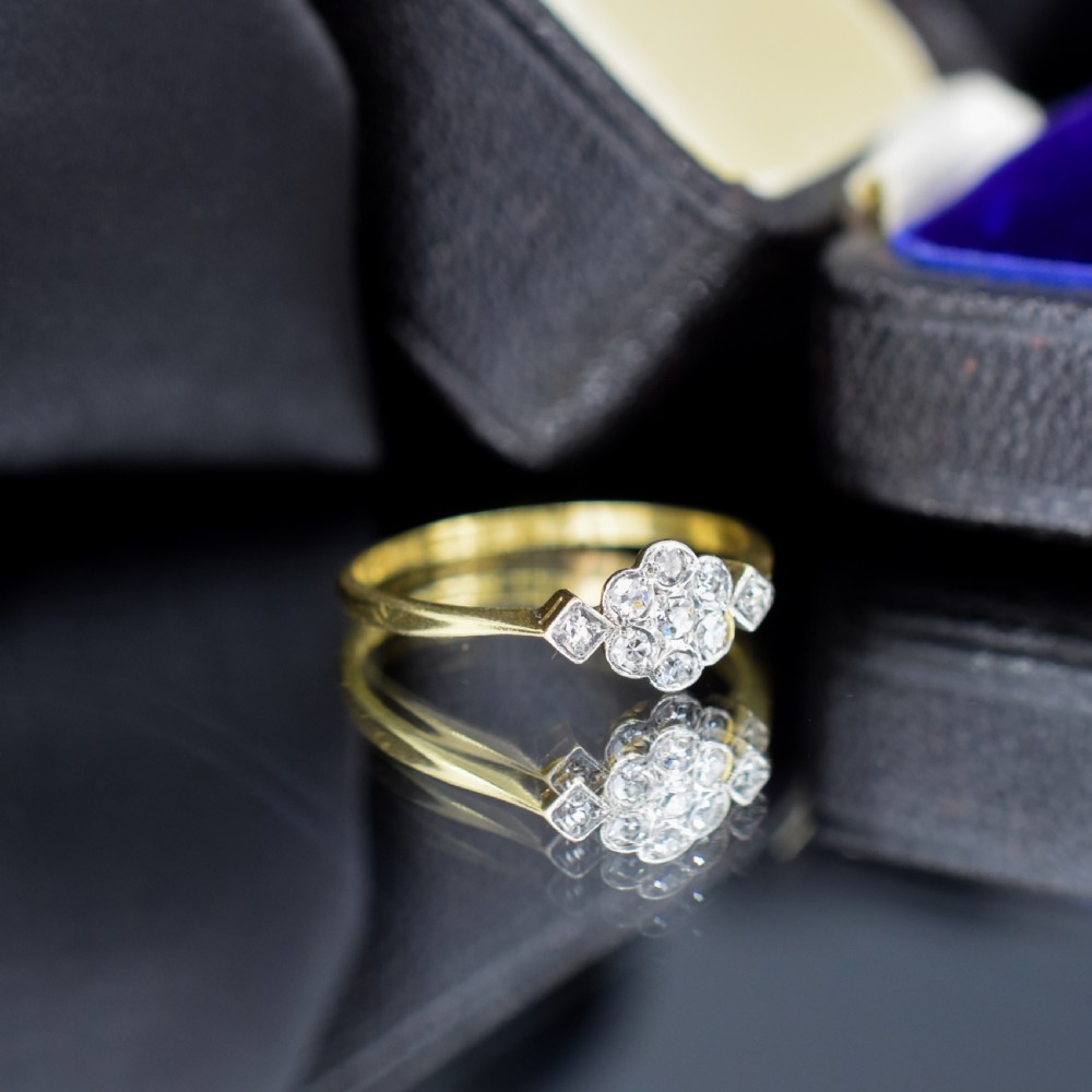 An Edwardian cluster ring crafted in yellow gold and platinum, featuring a central round diamond surrounded by a halo of diamonds with diamond-set shoulders. View IV