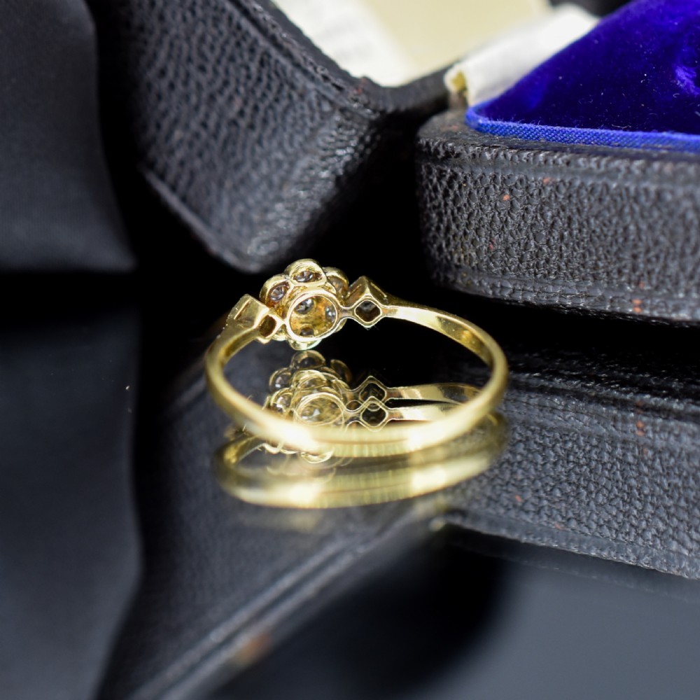 An Edwardian cluster ring crafted in yellow gold and platinum, featuring a central round diamond surrounded by a halo of diamonds with diamond-set shoulders. View V