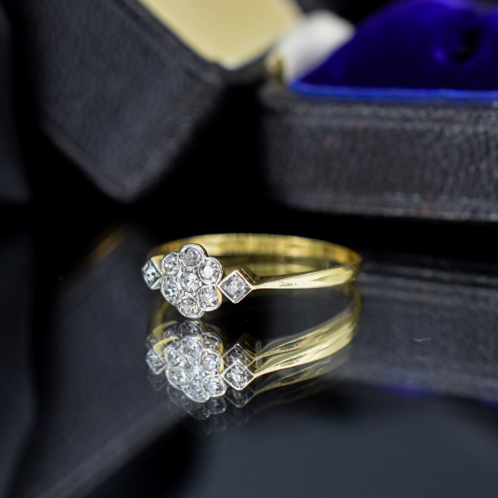 An Edwardian cluster ring crafted in yellow gold and platinum, featuring a central round diamond surrounded by a halo of diamonds with diamond-set shoulders. View VI