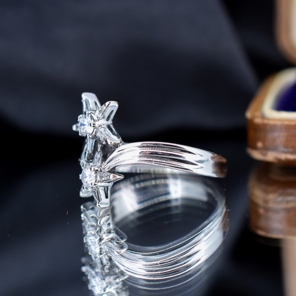 An 18ct white gold bypass ring featuring two star motifs set with brilliant-cut and baguette diamonds. View VI