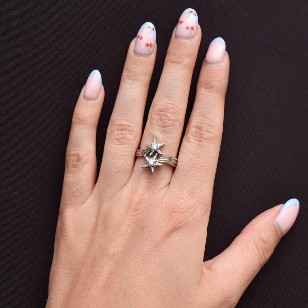 An 18ct white gold bypass ring featuring two star motifs set with brilliant-cut and baguette diamonds. View X