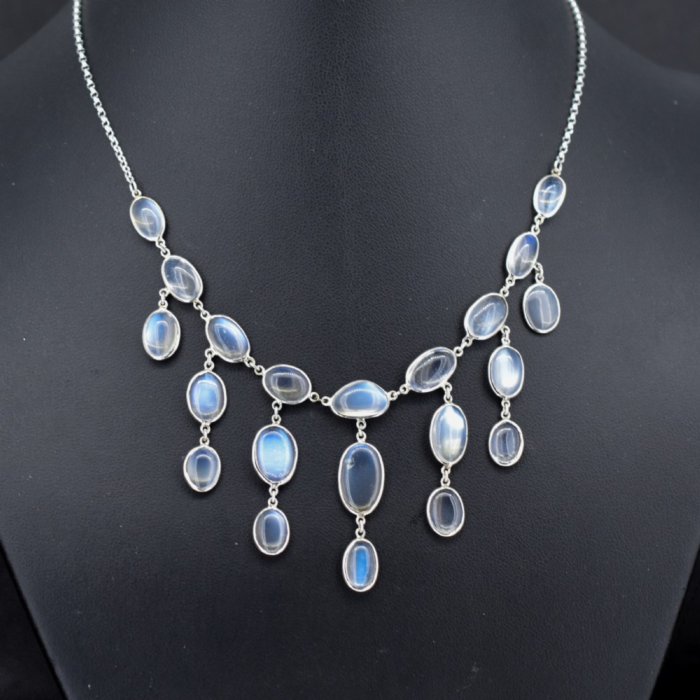 An antique silver festoon necklace featuring tiered oval cabochon moonstone drops suspended from a central chain. View II