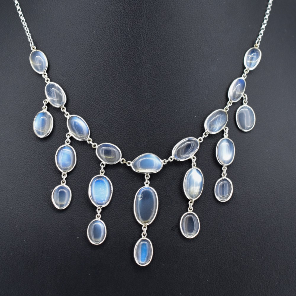 An antique silver festoon necklace featuring tiered oval cabochon moonstone drops suspended from a central chain. View III
