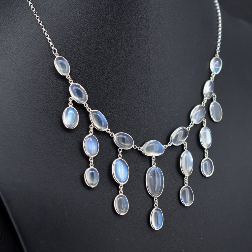 An antique silver festoon necklace featuring tiered oval cabochon moonstone drops suspended from a central chain. View IV