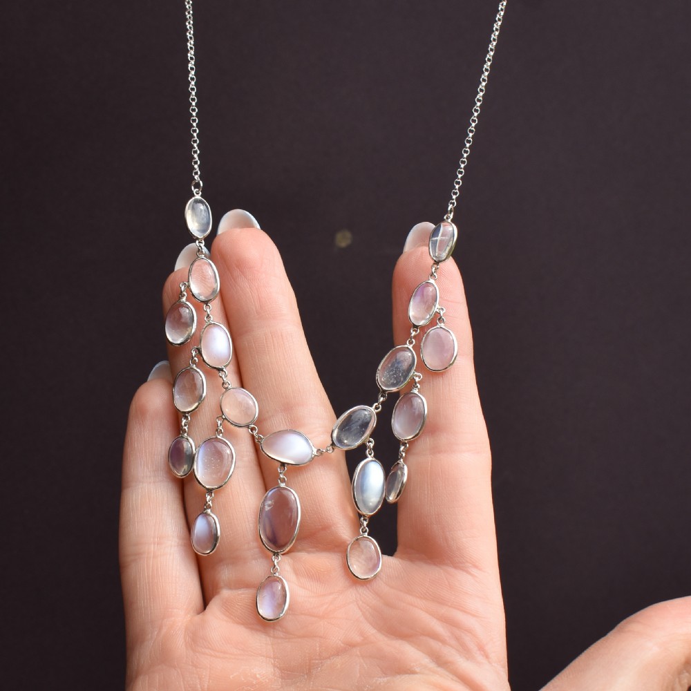 An antique silver festoon necklace featuring tiered oval cabochon moonstone drops suspended from a central chain. View VIII