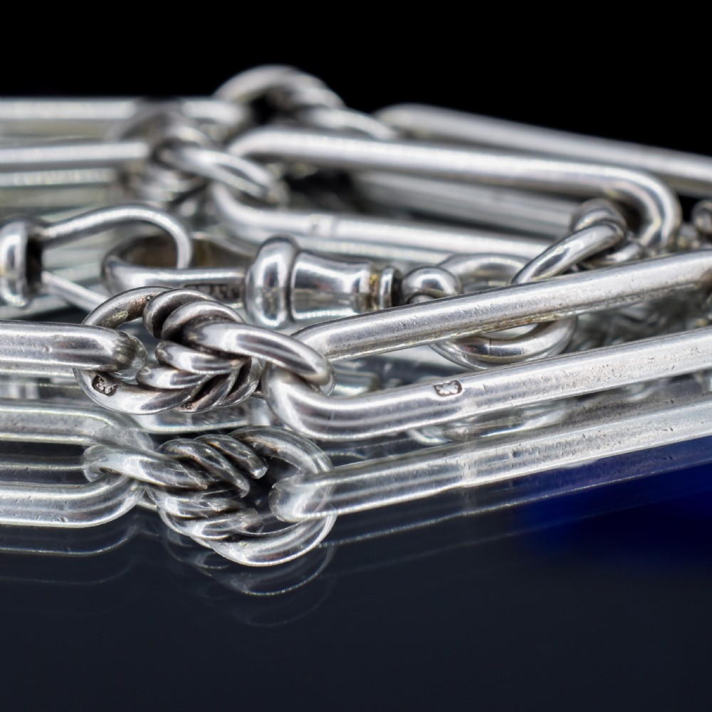 An antique sterling silver Albert watch chain featuring elongated trombone links interleaved with twisted love knots, complete with a T-bar and swivel clip. View V