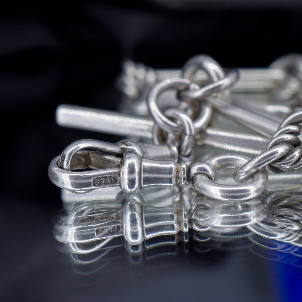 An antique sterling silver Albert watch chain featuring elongated trombone links interleaved with twisted love knots, complete with a T-bar and swivel clip. View VI