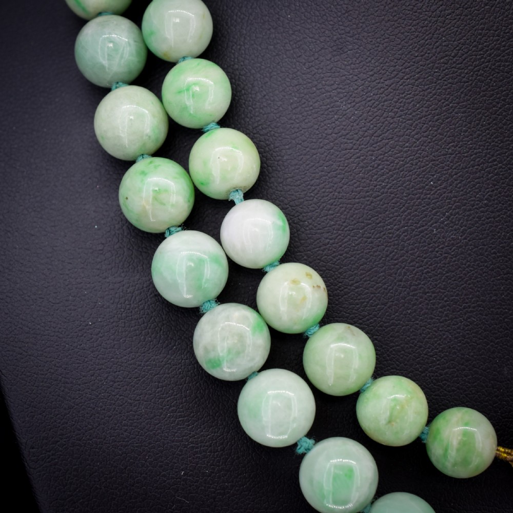 A double-strand necklace made of light green polished jade beads joined by a detailed gold hand-shaped figa clasp. View III