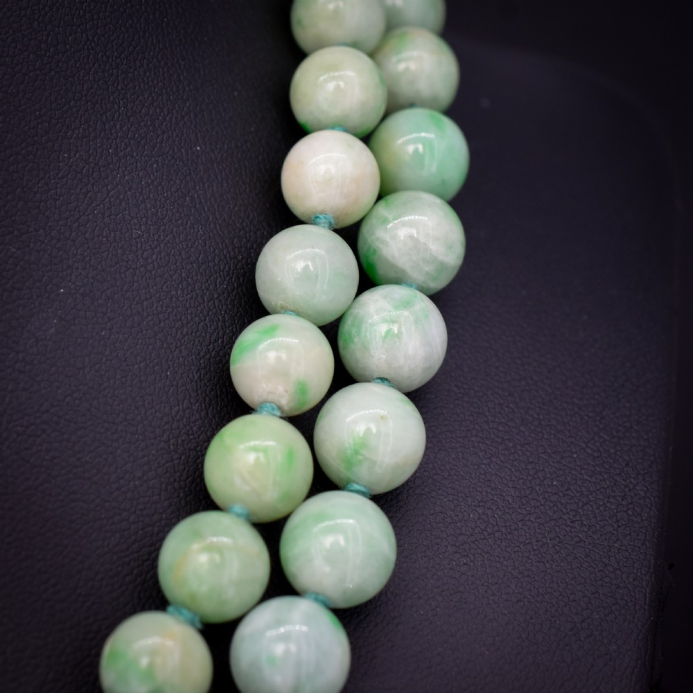 A double-strand necklace made of light green polished jade beads joined by a detailed gold hand-shaped figa clasp. View V