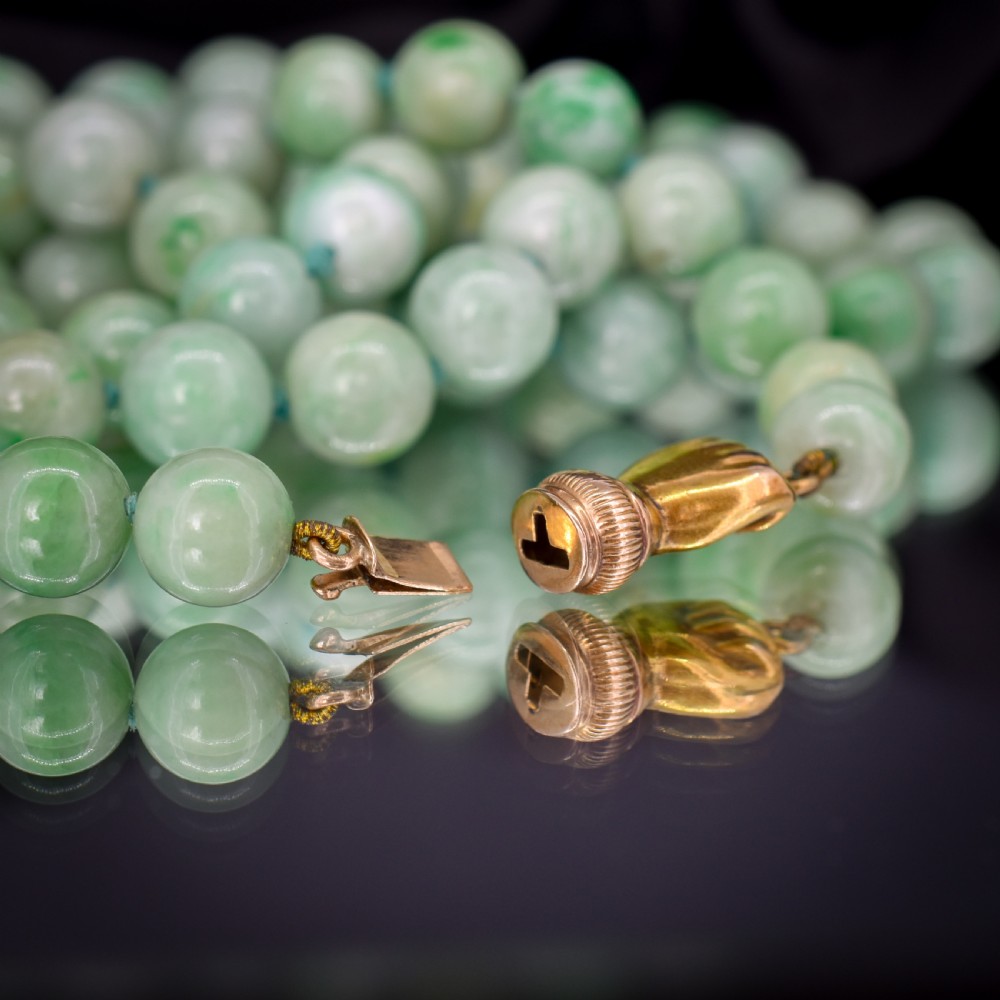 A double-strand necklace made of light green polished jade beads joined by a detailed gold hand-shaped figa clasp. View VIII