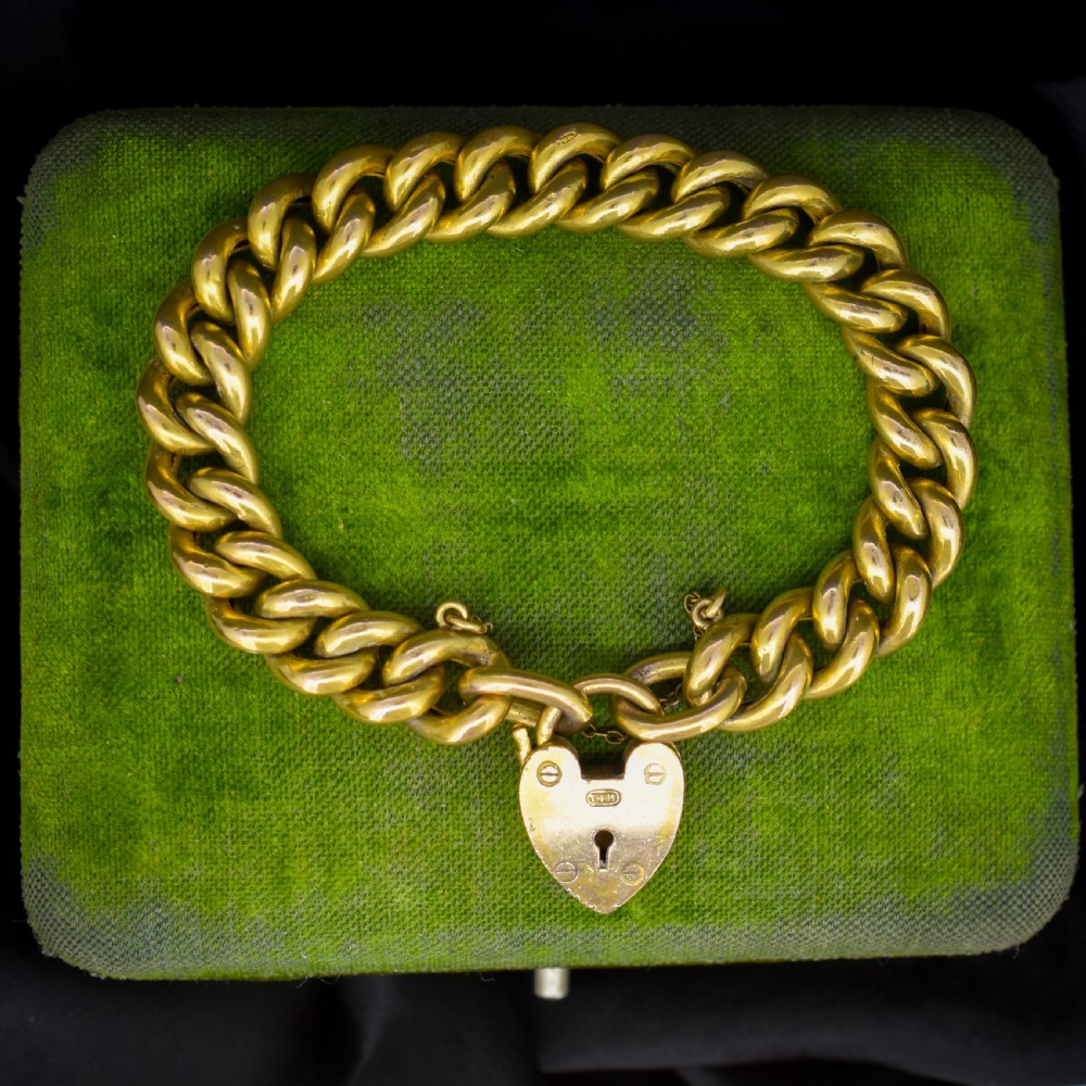 An antique rolled gold curb link bracelet featuring a heart-shaped padlock clasp and safety chain.