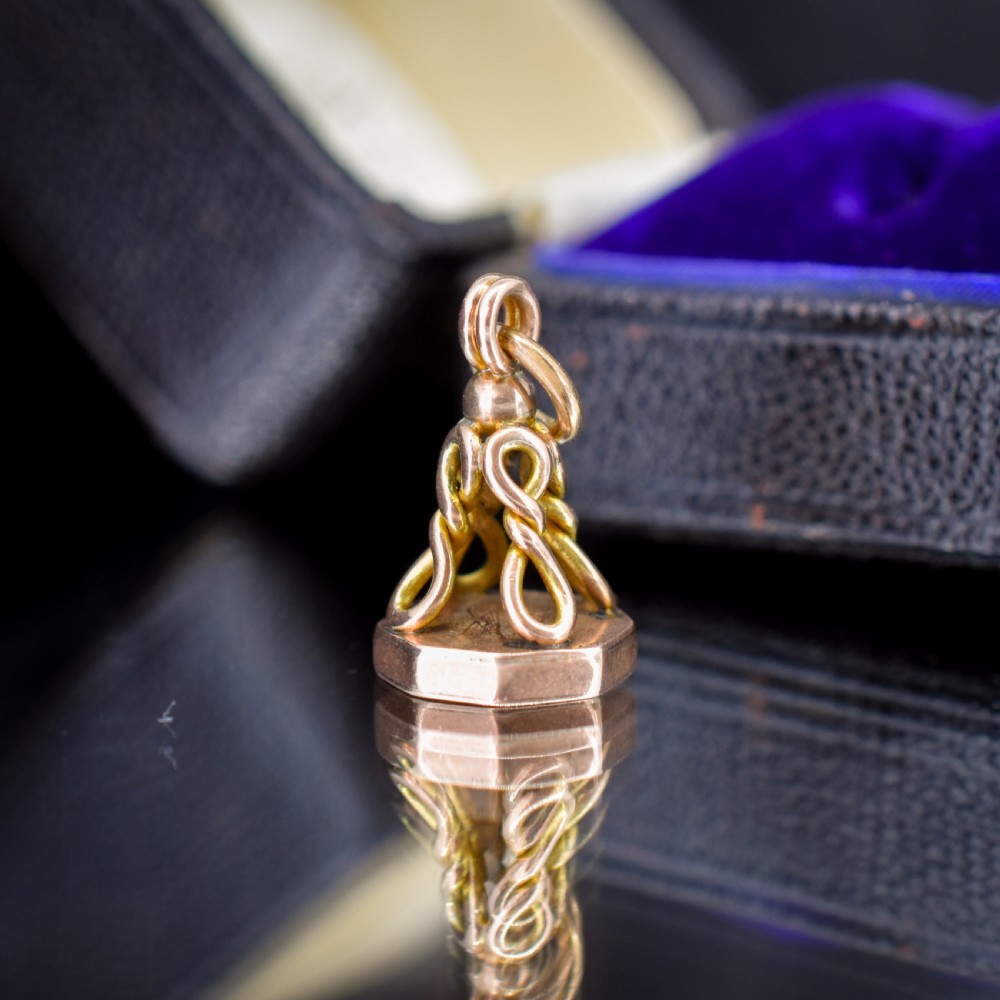 An antique 9ct yellow gold fob seal pendant featuring a looped wire handle design and a plain octagonal seal base. View IV