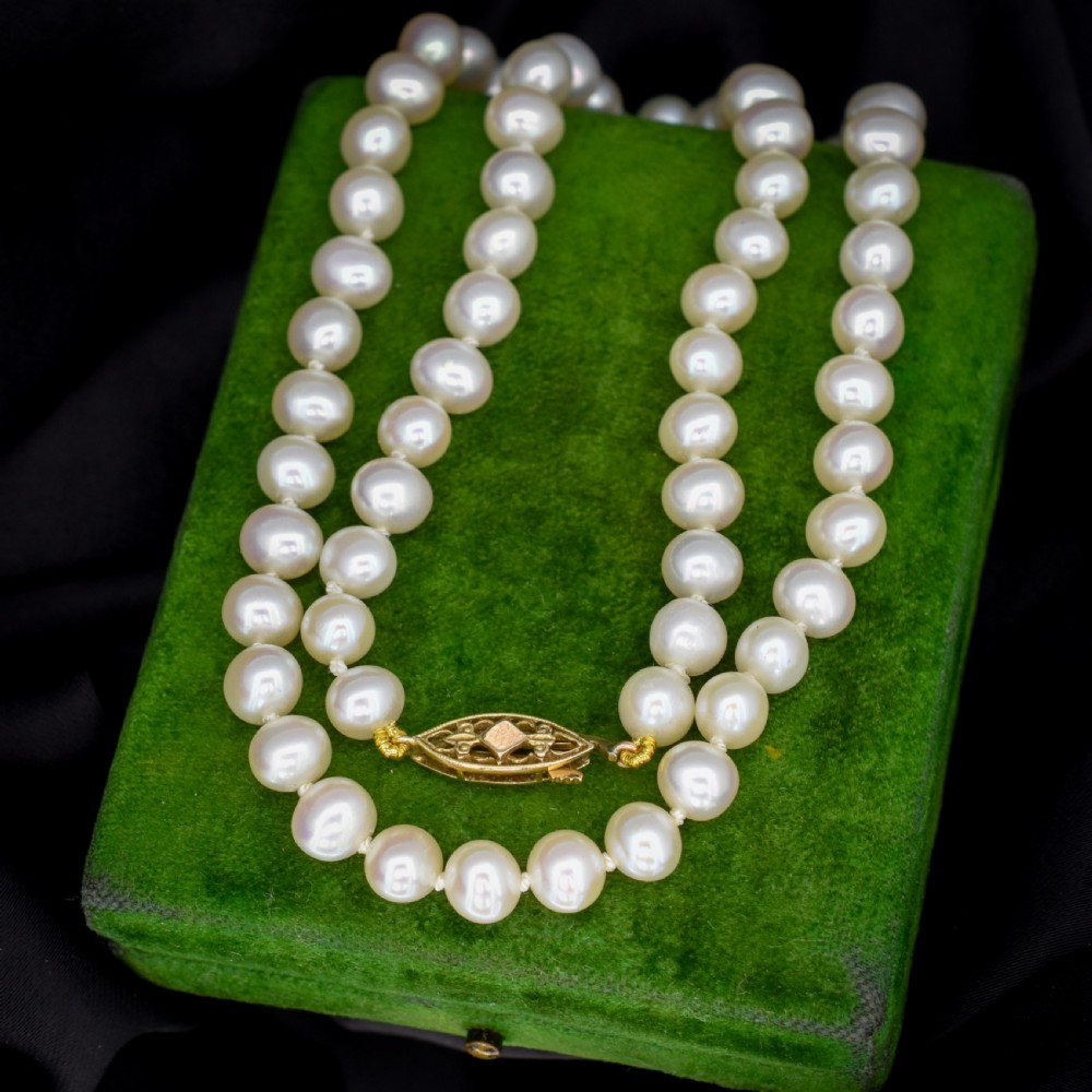 A single strand of graduated cream pearls fitted with a detailed yellow gold filigree clasp.