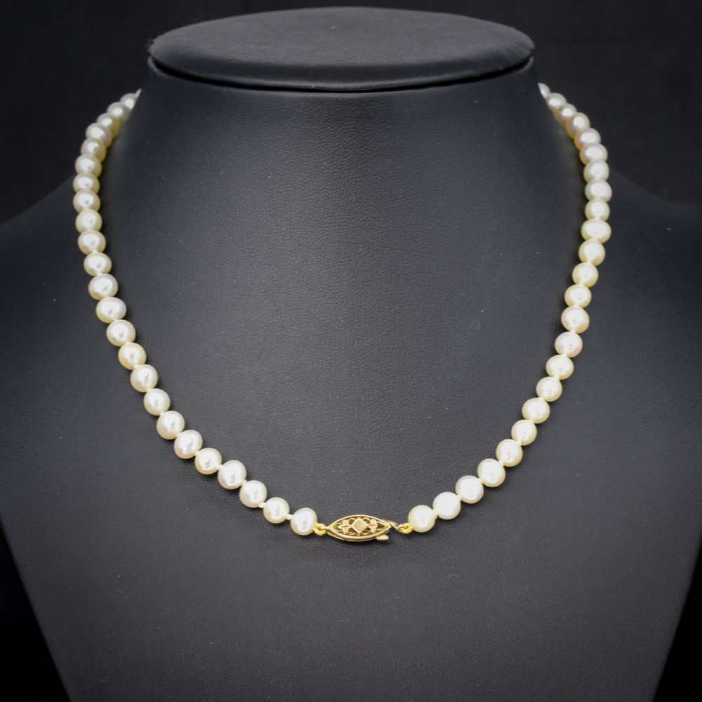 A single strand of graduated cream pearls fitted with a detailed yellow gold filigree clasp. View II