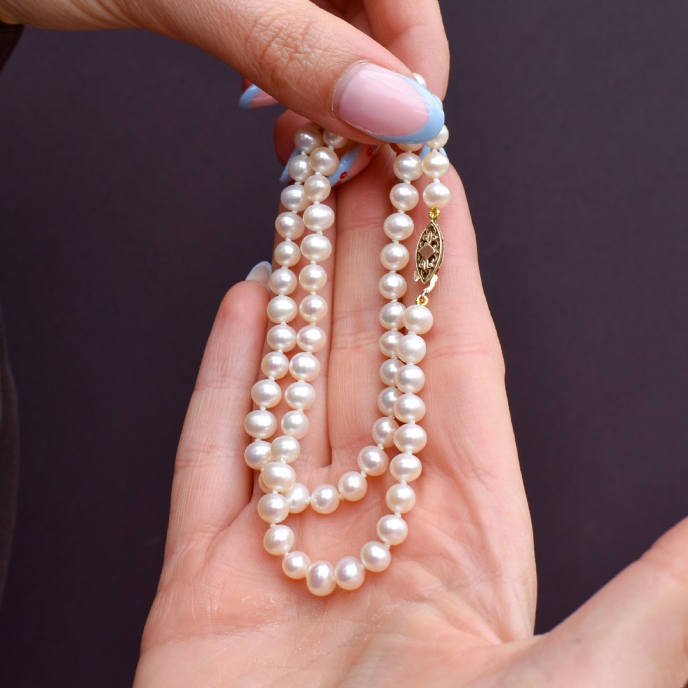 A single strand of graduated cream pearls fitted with a detailed yellow gold filigree clasp. View IX