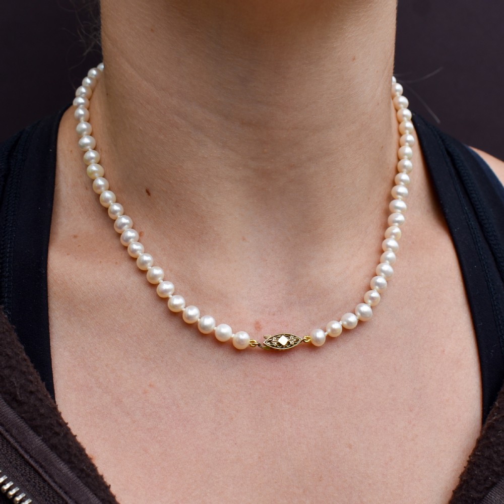 A single strand of graduated cream pearls fitted with a detailed yellow gold filigree clasp. View X