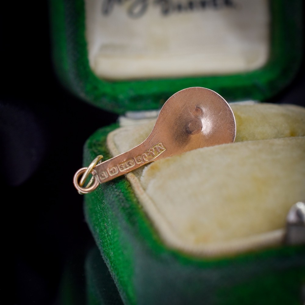 A small antique 9ct rose gold charm shaped like a tennis racket with a raised central tennis ball. View V