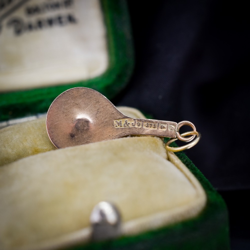 A small antique 9ct rose gold charm shaped like a tennis racket with a raised central tennis ball. View VI