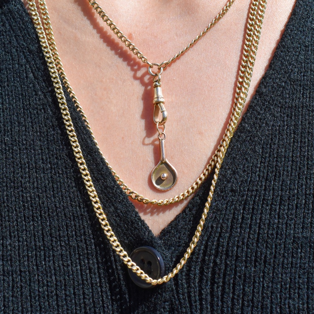 A small antique 9ct rose gold charm shaped like a tennis racket with a raised central tennis ball. View IX