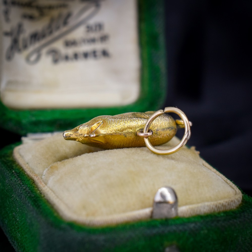 An Edwardian 9ct yellow gold pig charm featuring a textured three-dimensional body and an attached suspension ring.