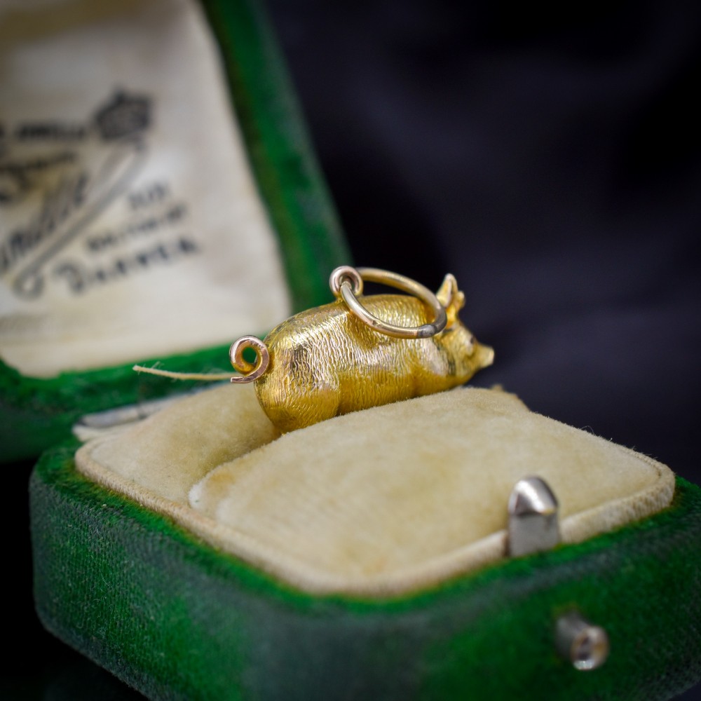 An Edwardian 9ct yellow gold pig charm featuring a textured three-dimensional body and an attached suspension ring. View III