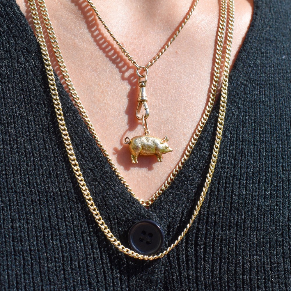 An Edwardian 9ct yellow gold pig charm featuring a textured three-dimensional body and an attached suspension ring. View VI