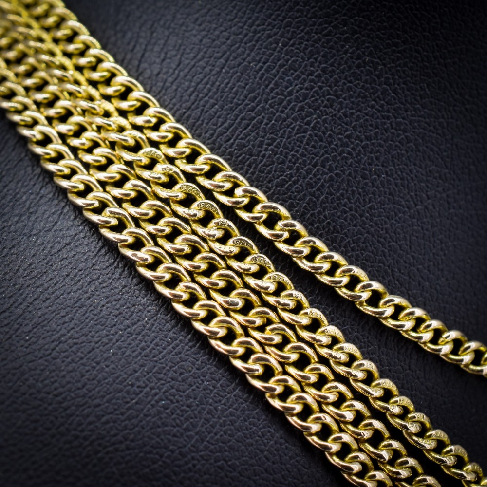 An antique 9ct yellow gold curb link guard chain layered in multiple loops with a dog clip fastener on a black bust. View II