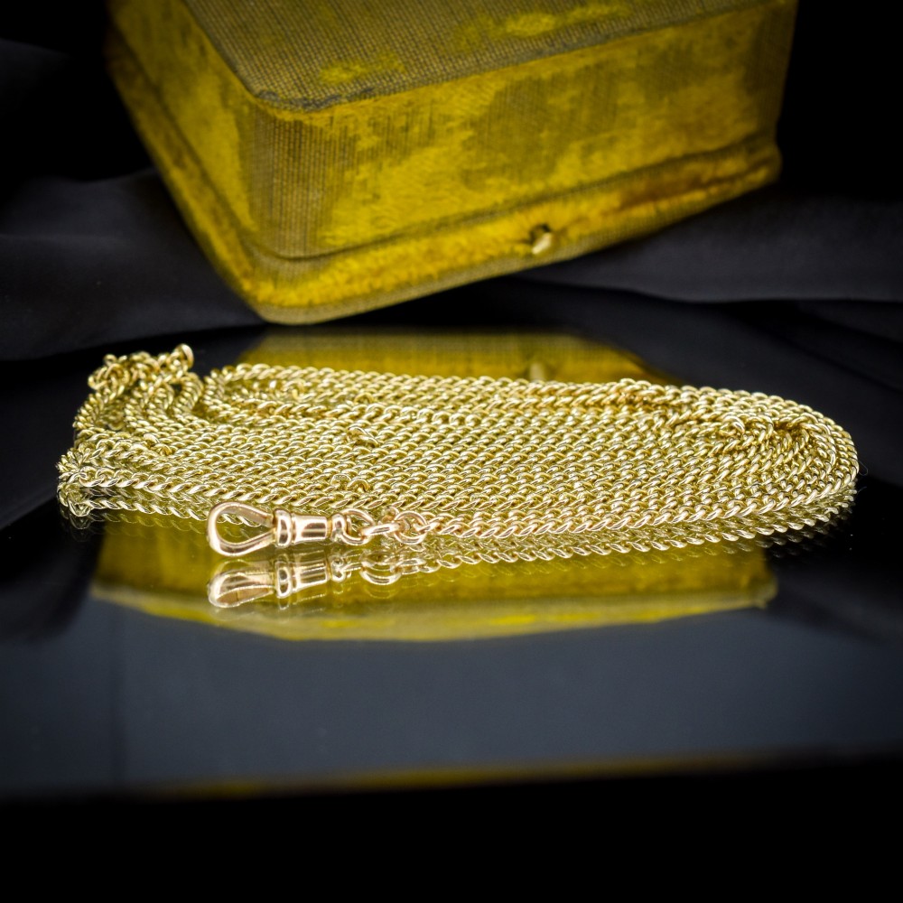 An antique 9ct yellow gold curb link guard chain layered in multiple loops with a dog clip fastener on a black bust. View V