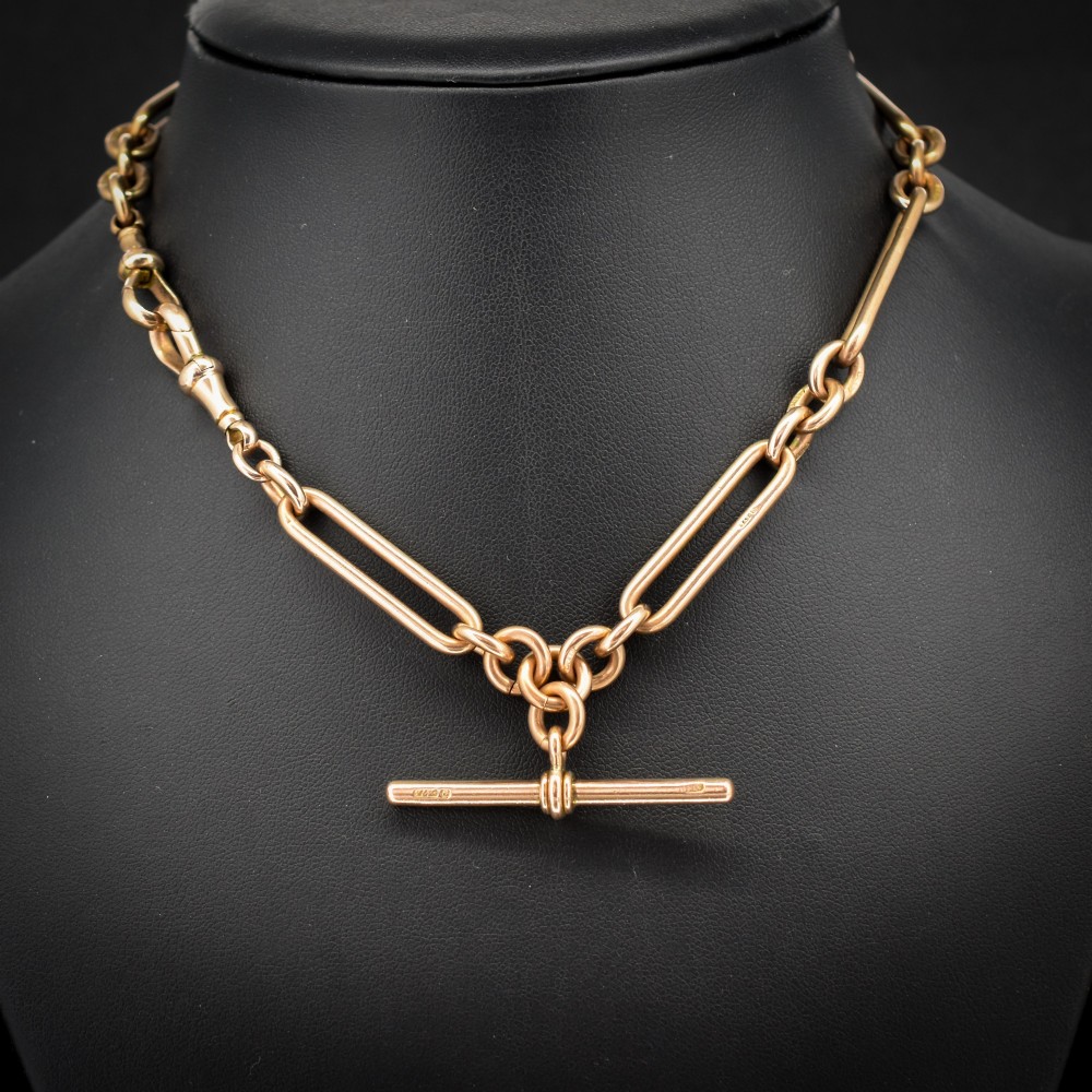 An Edwardian 9ct gold trombone link chain necklace with a central T-bar drop and dog clip clasp.